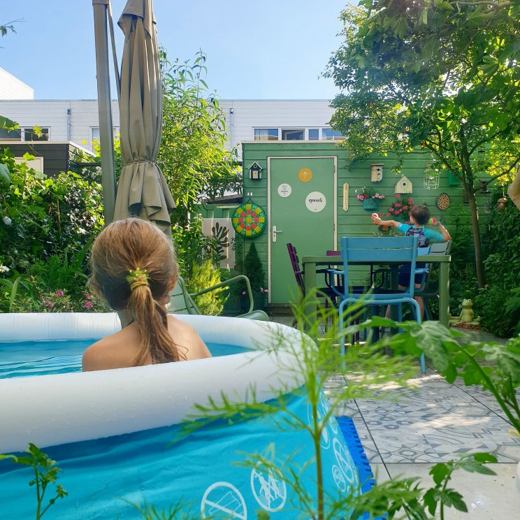 Tips voor een kindvriendelijke, kleurrijke en groenblijvende tuin. We hebben een plek waar het zwembadje kan staan. Meestal staan daar de tuinstoelen, maar die kunnen we makkelijk verplaatsen. Ook hebben we een buitendouche, een hele simpele. Daar kunnen de kinderen lekker onder afkoelen, of buiten douchen als ze in de buurt gezwommen hebben.