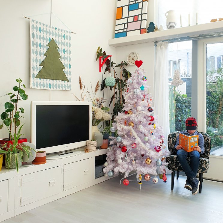 Binnenkijker: kleurrijke woonkamer met witte basis plus groen en vintage. Fijne plek in relaxstoel en uitzicht op de tuin. 