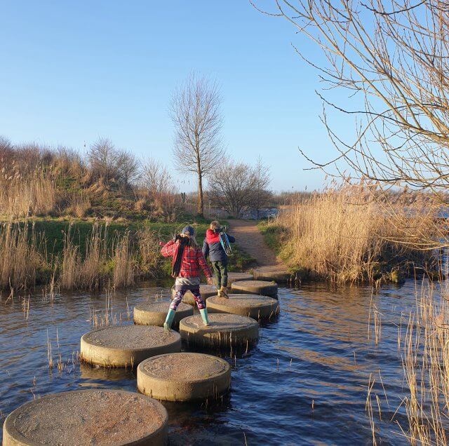 Wandelen met kinderen in de buurt van Amsterdam: plekken met speeltuin. Zoals de Toolenburger Plas in Hoofddorp, je kunt een heel leuk rondje om de plas wandelen. Dan kom je langs speeltuinen, speelnatuur, fitnessplekken, een voetbalkooi, een skatebaan en strandjes. Ook is er een restaurant.