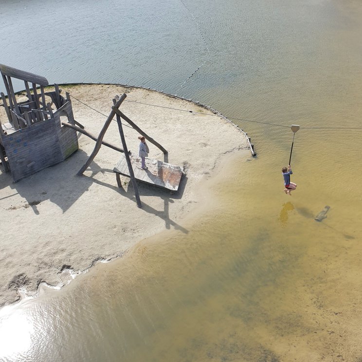 Hof van Saksen review: luxe vakantiepark voor kinderen én tieners. Strandspeeltuin met speeleiland in het water. Daar kom je alleen over het water. Aan de ene kant is dat via een soort klimparcours, aan de andere kant met een kabelbaan. 