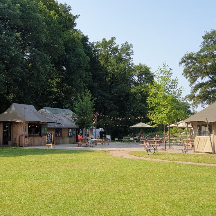 Huttopia de Roos: review van kindvriendelijke natuur camping in Overijssel. Er zijn veel verschillende speeltuinen, dit is de speeltuin. Op de camping is een afhaalrestaurantje of eigenlijk een food truck. In de zomervakantie is die zes dagen per week open. De ene dag stonden er hamburgers op het programma, de andere dag pizza. Die kun je op het terras opeten of als afhaal meenemen. Daarnaast is er een bar waar je de hele dag wat te drinken kunt halen. 