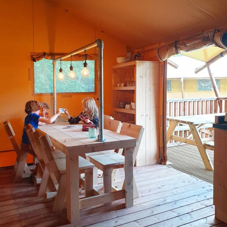 De safaritenten glamping Landal Gooise Heide liggen midden in het bos. Wij verbleven in de 4-6-persoons safaritent. Deze tent heeft twee slaapkamers, een met een 2-persoonsbed en een met twee stapelbedden. De woonkamer heeft een grote tafel, zithoek, keuken en veel ruimte. Daarnaast heb je een eigen badkamer. Buiten op de veranda zijn zowel een picknicktafel als een loungehoek. Fijn voor hondenliefhebbers: je mag je hond meenemen. Sommige safaritenten zijn ook speciaal voor honden uitgerust, bijvoorbeeld met een bench en bakken. 