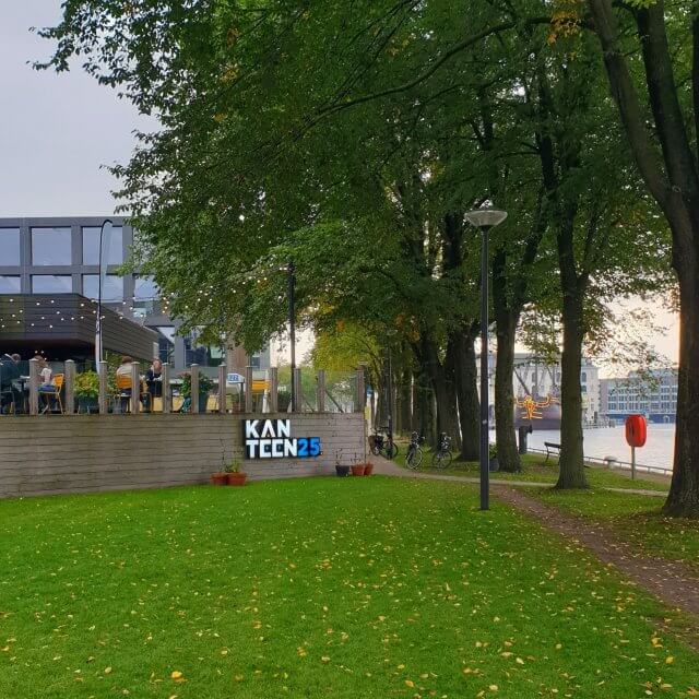 Kanteen25 Amsterdam: duurzaam restaurant met stoere speelruimte op Marineterrein, leuk voor kinderen en tieners. Het terras van Kanteen25 is kortgeleden gekozen tot het mooiste terras van Amsterdam. Geen wonder: het ligt aan het water van de Dijksgracht. Vanaf het terras heb je daarnaast uitzicht op Nemo en het Scheepvaartmuseum. Maar het ligt ook in het groen, bij mooi weer staan er extra biertafels en zitzakken in het gras.