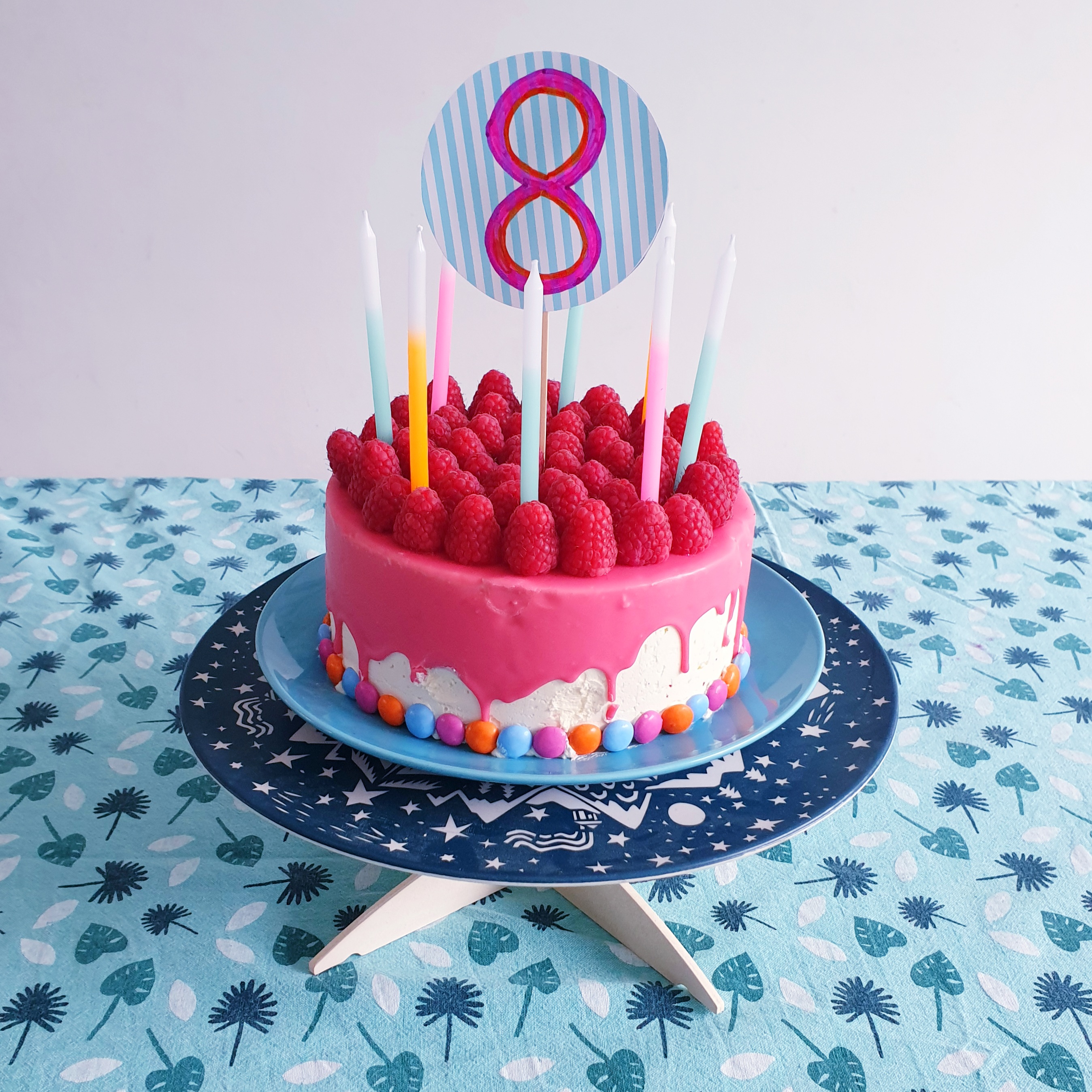 Bakken met kids: 25 leuke recepten voor kinderen. Deze dripcake is heel makkelijk en ziet er super leuk uit. Deze dripcake is roze, met neon oranje en fluo blauw. Versierd met smarties en frambozen.