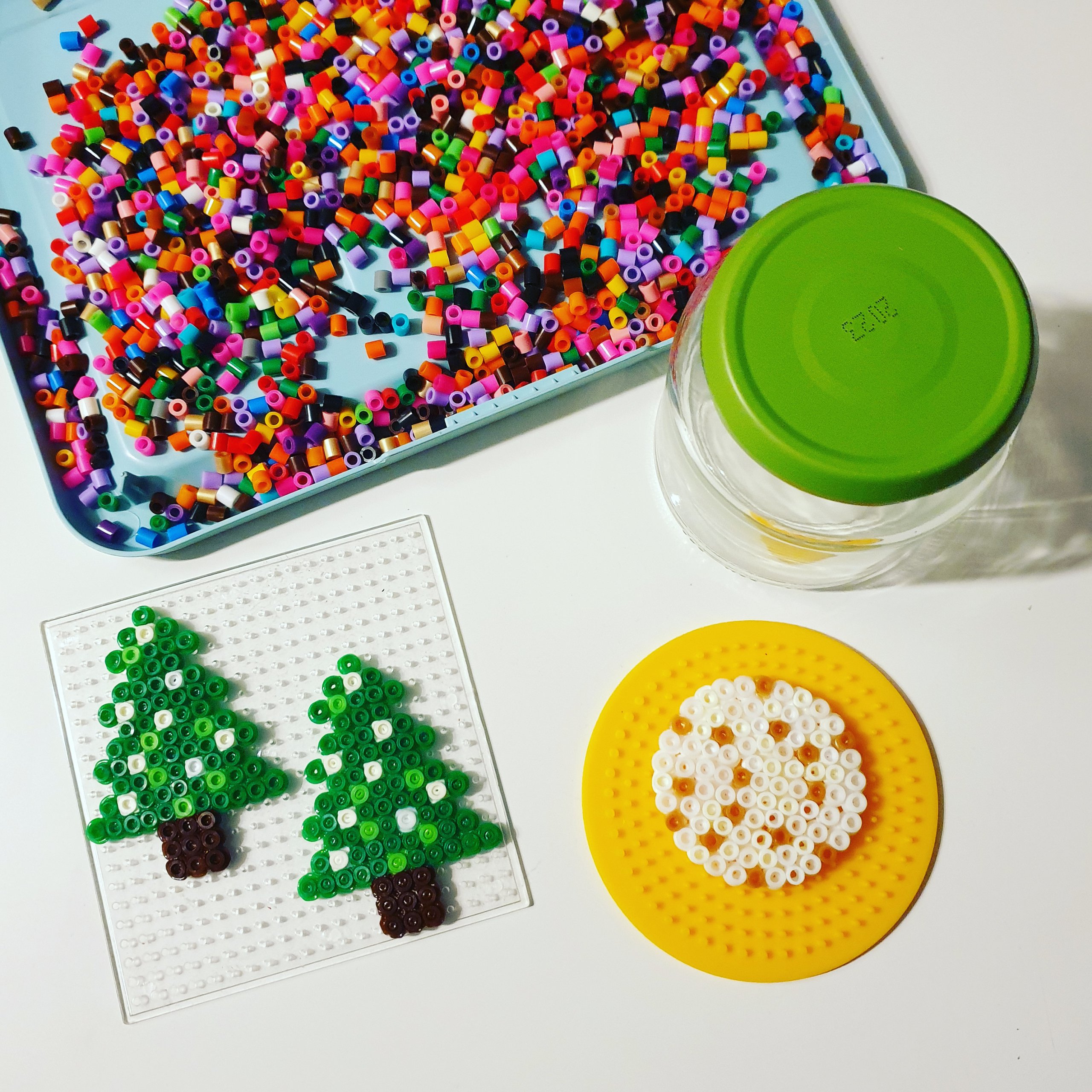 Kerst knutselen met strijkkralen: leuke ideeën. Met strijkkralen kun je ook een leuke sneeuwbol met kerstboom voor kerst knutselen. Daarvoor heb je naast strijkkralen ook een glazen conservenpotje en pailletten nodig.