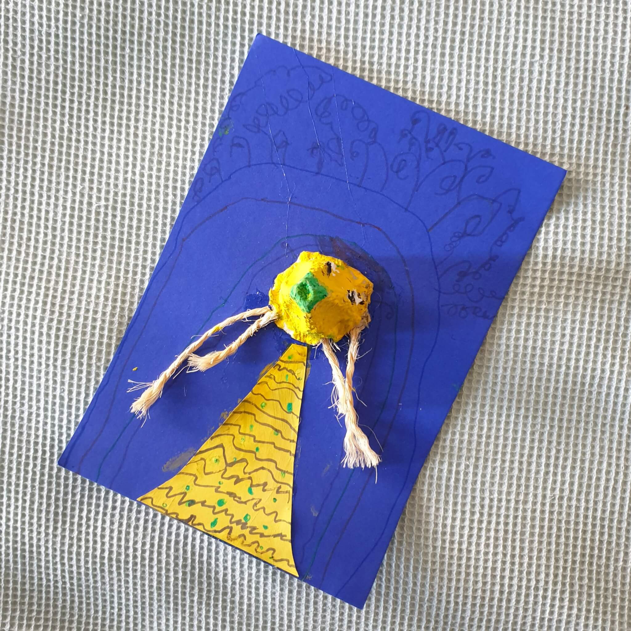 Ideeën om te knutselen met peuter en kleuter. Dit poppetje knutselde kleine meis op school. Ze gebruikte dik blauw papier als basis en knipte een jurkje van geel papier. Uit een eierdoos knipte ze één vakje en verfde het geel. Daarnaast schilderde ze er een neus en oogjes op. De haren zijn gemaakt van stukje touw. 