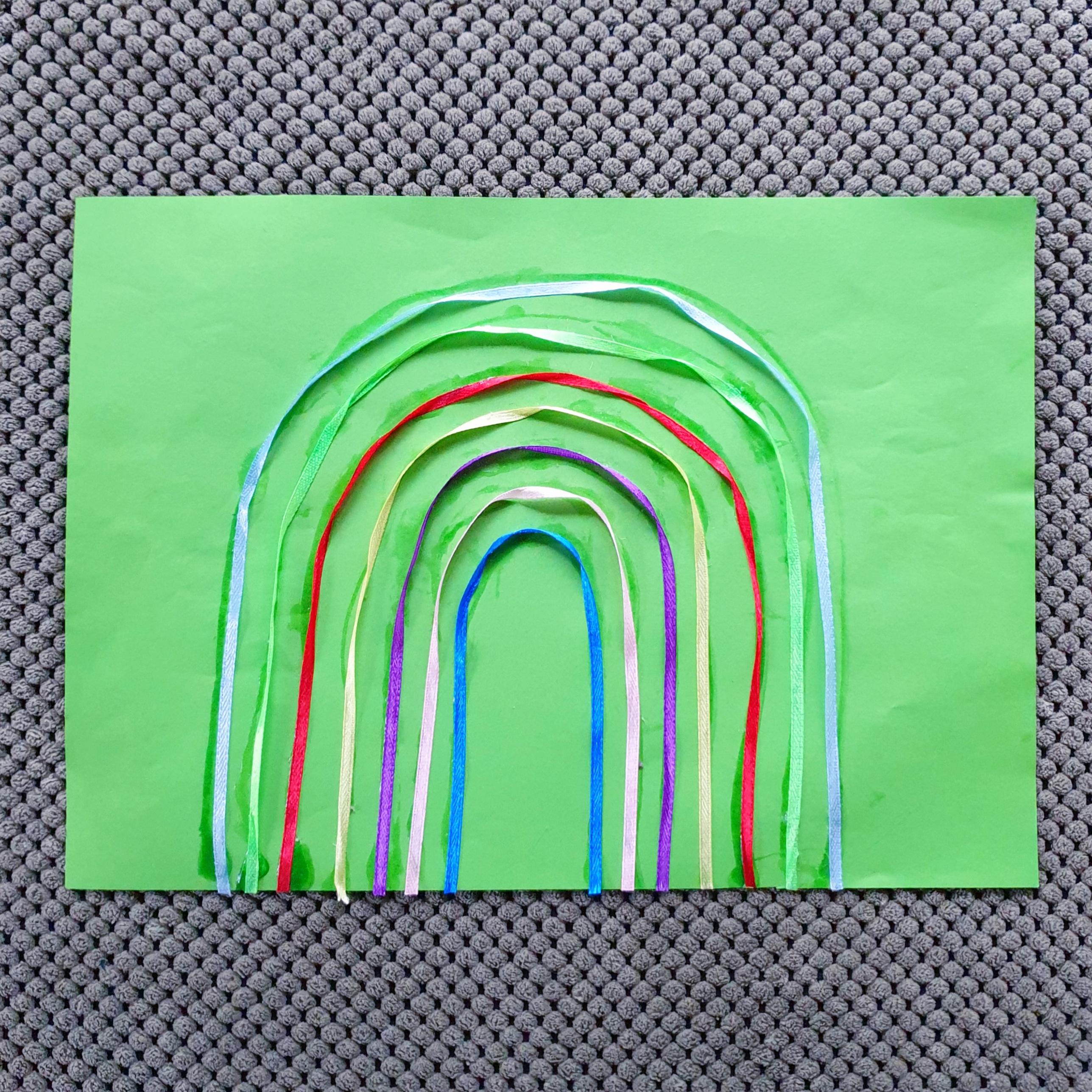 101 ideeën om te knutselen met kinderen. Deze regenboog maakten we van lintjes en gekleurd papier. We begonnen met het binnenste lintje en werkten naar buiten toe. Eerst maakten we met knutsellijm een boogje op het papier. Daarna plakten we het lintje er op. 