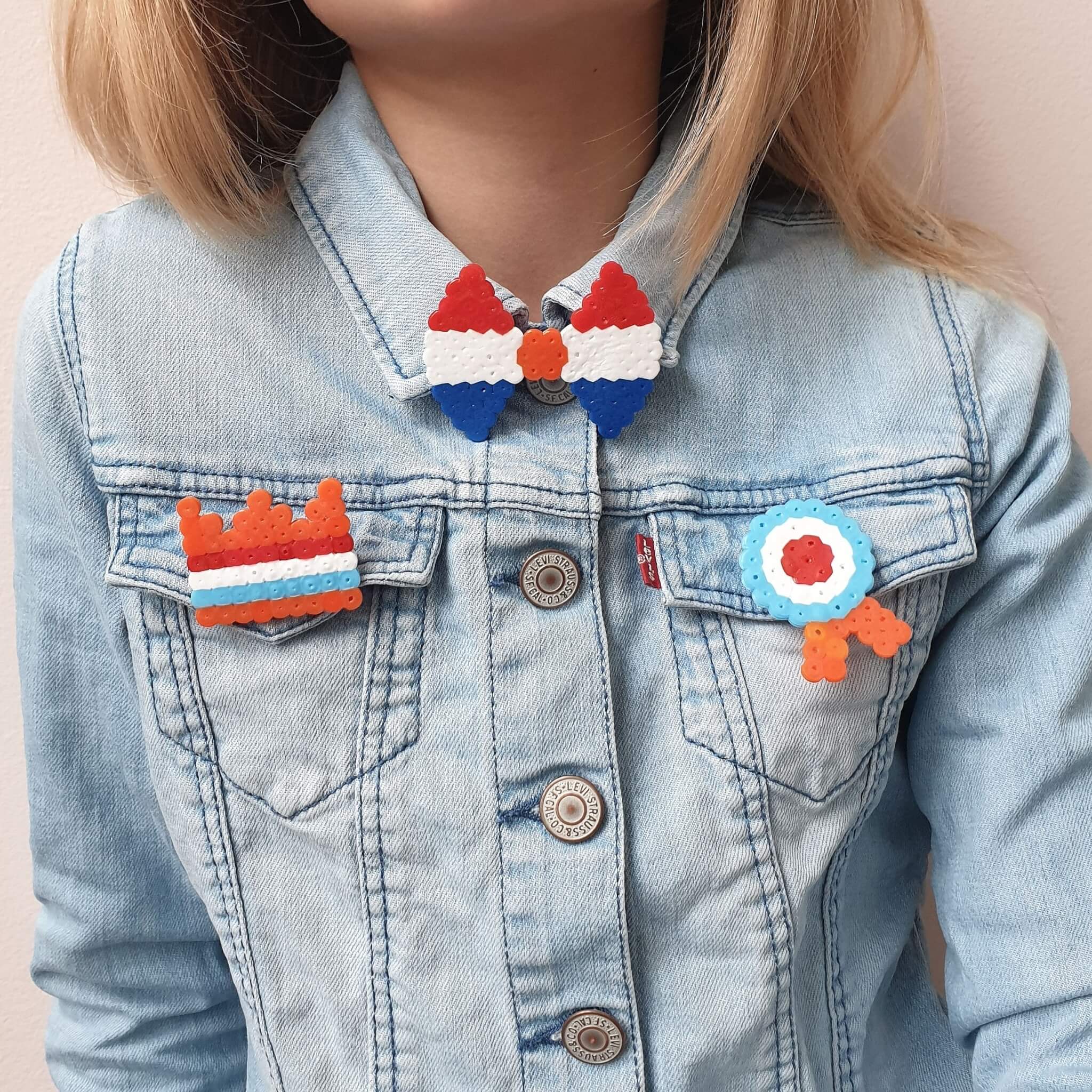 Knutselen voor Koningsdag en Oranje. De kids waren op zoek naar iets leuks om te verkopen op de vrijmarkt. Strijkkralen broches moesten het worden, besloten ze. We maakten ze heel eenvoudig. Een oranje kroon, een medaille, een strikje en een rood wit blauw hartje.