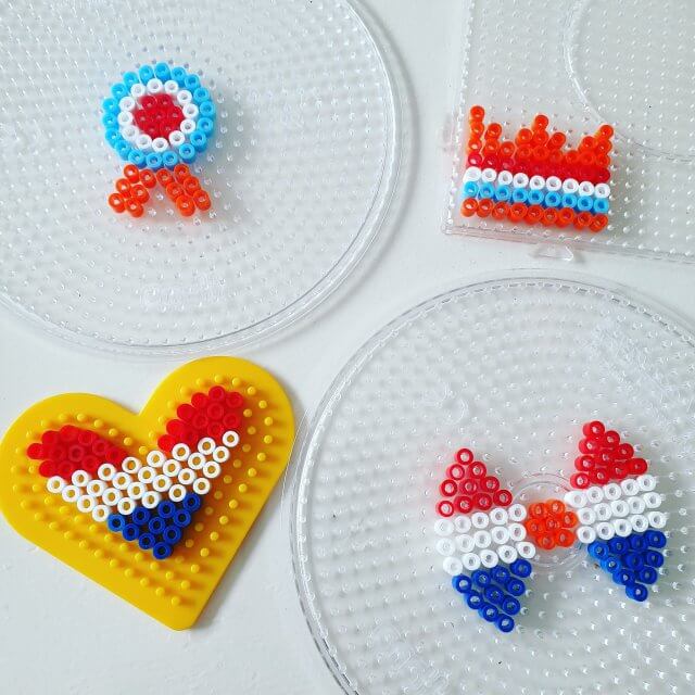 Knutselen voor Koningsdag en Oranje. De kids waren op zoek naar iets leuks om te verkopen op de vrijmarkt. Strijkkralen broches moesten het worden, besloten ze. We maakten ze heel eenvoudig. Een oranje kroon, een medaille, een strikje en een rood wit blauw hartje. 