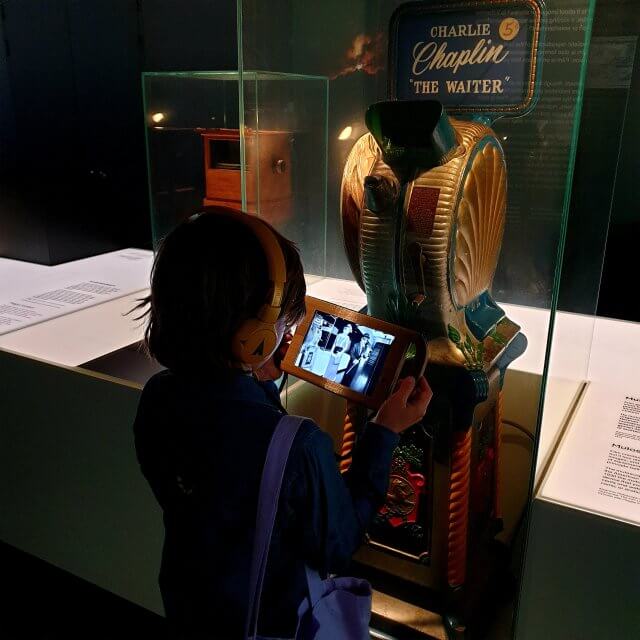 Het filmmuseum EYE heeft een aantal dingen ontwikkeld om speciaal met kinderen te doen. Zo is er de EYE walk videotour voor kinderen van 7 tot 12 jaar. Zoonlief en ik deden beide deze tour van ongeveer een half uur. Je krijgt een tablet met een koptelefoon, waarmee je langs de collectie wandelt. Historische personages lijken tegenover je te staan om hun verhaal te vertellen, waardoor ze tot leven komen. Ook de door hun ontwikkelde of gebruikte apparaten gaan daardoor leven.