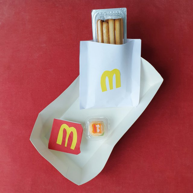 Corona proof voorverpakte traktatie ideeën: verjaardag op school of crèche, zoals deze McDonald's traktatie. Een klasgenootje trakteerde dit McDonald's setje. De basis zijn La Vache Qui Rit Cheez dippers, daarvan werd het kaasbakje losgeknipt van het bakje met de broodsticks. Op het kaasbakje plakten ze een rood papiertje en vervolgens de gele McDonald's M er op, zo werd het frietsaus. Het bakje met de broodsticks werd verpakt in een zakje van wit papier, ook met de gele M er op, dat is het frietzakje. De mini hamburger is gemaakt van snoepjes.