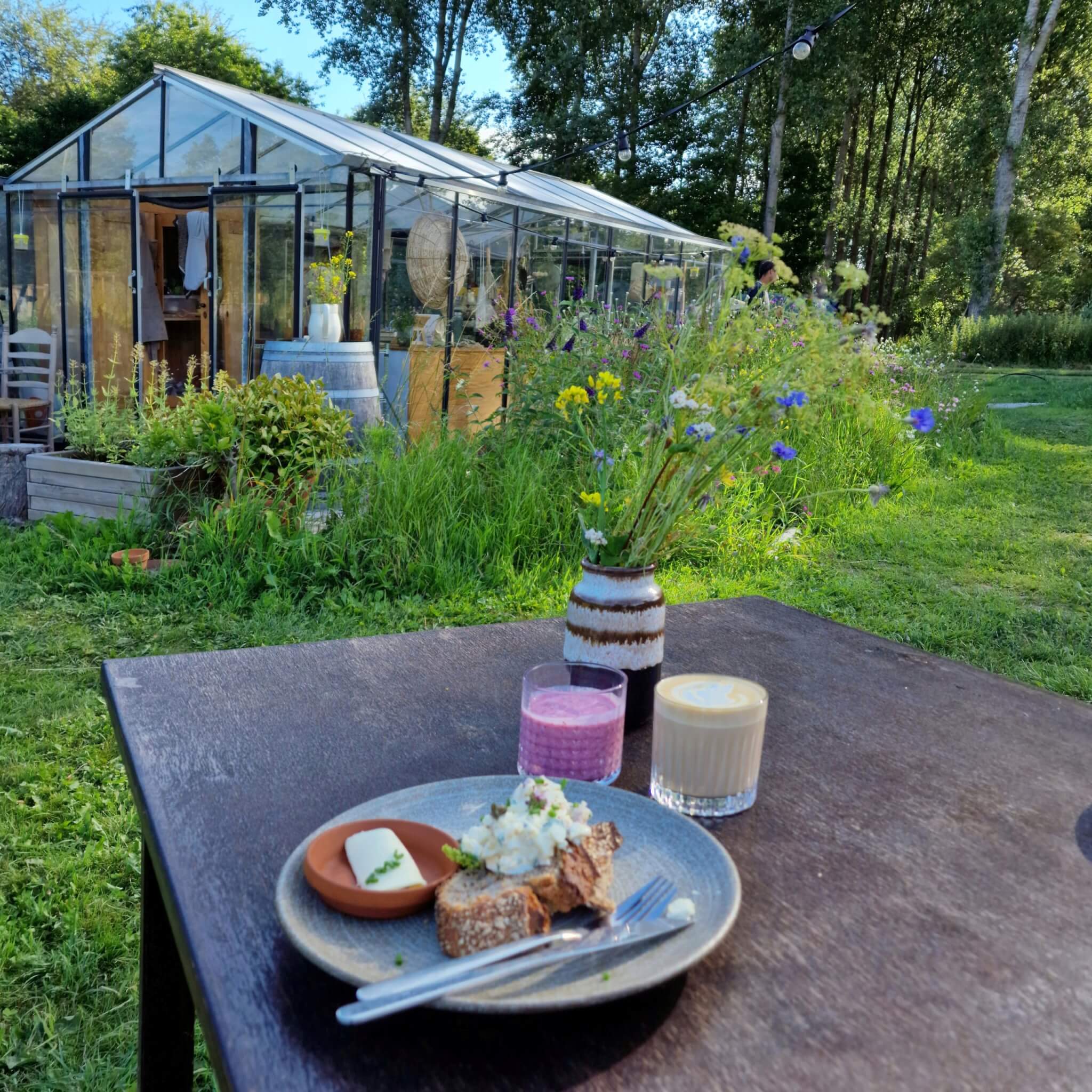 Terra Wolde met kinderen: eco buiten hotel en luxe camping. Terra Wolde heeft een eigen restaurant, genaamd Pomponius. Je eet hier super idyllisch tussen de kas (de keuken) en de weelderige tuin vol groente en eetbare bloemen.