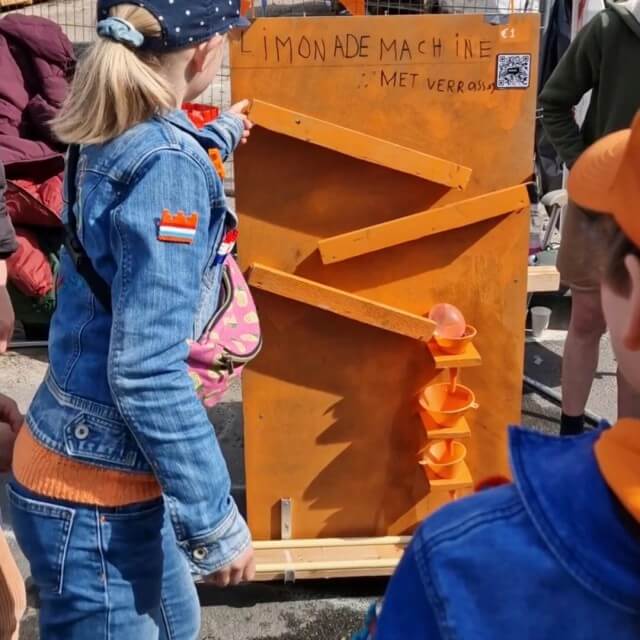 Knutselen voor Koningsdag en Oranje. De kinderen van Sanne bedenken ieder jaar een nieuw spel. Dat knutselen ze vervolgens van hout, met hulp van opa. Hoe gaaf is dit: een heuse limonade machine voor de vrijmarkt knutselen! Het autootje rijdt naar beneden en prikt de waterballon vol limonade lek. Dat loopt vervolgens via trechters in een bekertje. 